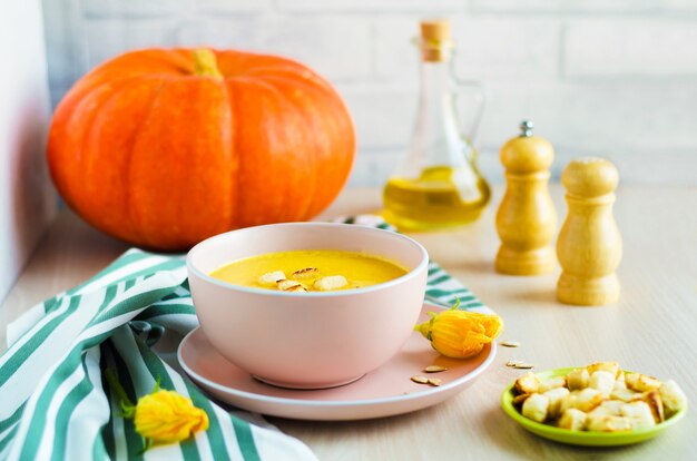 Zuppa cremosa di zucca con semi e crostini di pane in una ciotola.