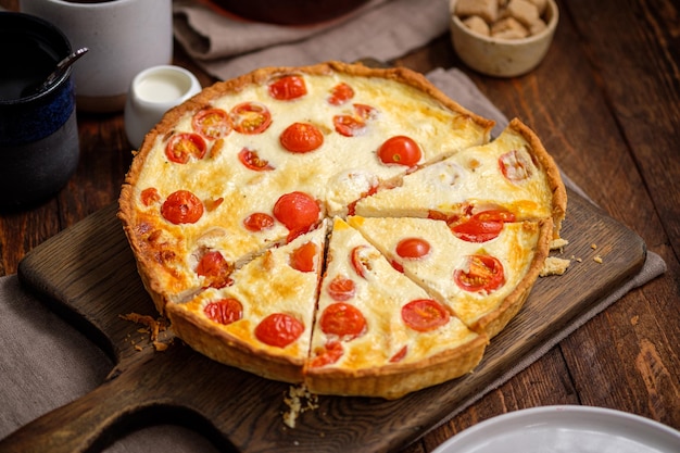 Creamy shortbread pie quiche with cherry tomatoes and chicken in the village on a wooden table