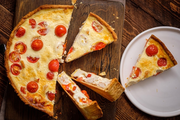 Creamy shortbread pie quiche with cherry tomatoes and chicken in the village on a wooden table