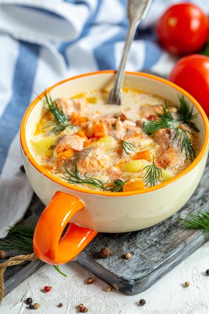 Creamy soup with salmon and vegetables in a bowlxA