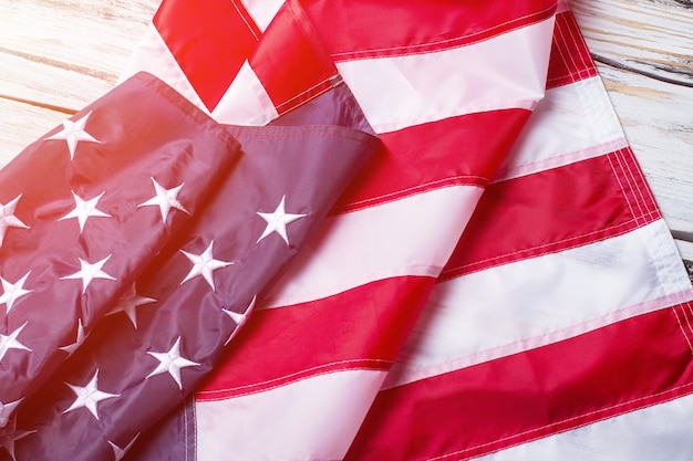 Creased flag of USA. USA national flag in sunlight. Banner laying on wooden shelf. Peace, prosperity and future.