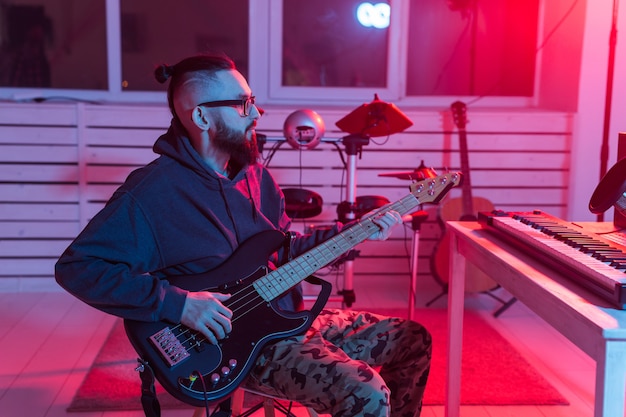 Photo create music and a recording studio concept. bearded funny man guitarist recording electric bass