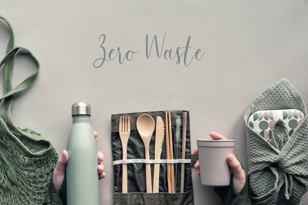 Creatief bovenaanzicht, nul verspild lunchconcept. Plat liggende, lunchbox set met bamboe bestek, herbruikbare doos, canvas tas en hand met koffie-naar-go cup op ambachtelijk papier. Tekst "Zero Waste".