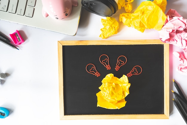 Foto creatief concept met proppen papier bal en gloeilamp paperclip, laptop en potloden