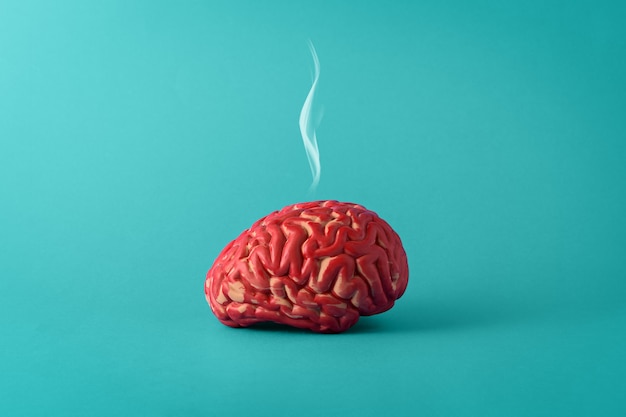 Creatief concept van een vermoeid brein op een blauwe achtergrond. Menselijke hersenen met rook.