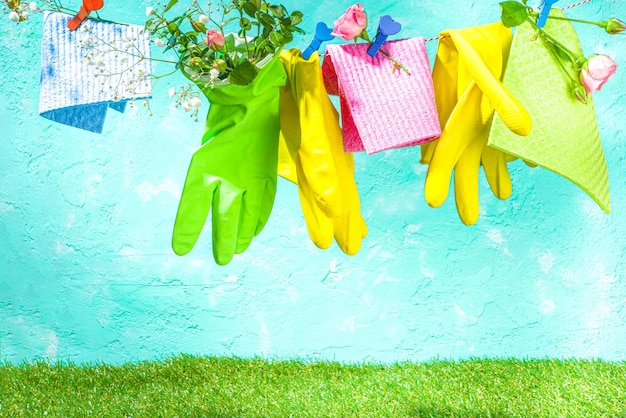Creatief helder lenteschoonmaakconcept. Gereedschap, flessen, accessoires voor het schoonmaken van huis met lentebloemen en bladeren hangen aan de waslijn, doos, helder zonnig licht kopieerruimte