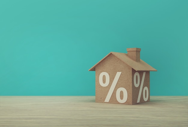 Creatief idee van huis modeldocument en het symboolpictogram van het percentageteken op houten lijst. Onroerend goed investeringen onroerend goed en huis hypotheek financieel concept.