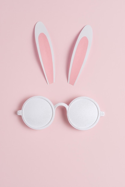 Creatief Pasen-concept met konijnenoren en witte zonnebril op roze achtergrond Minimaal Pasen-concept