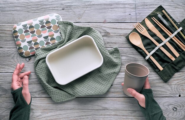 Creatief plat lag, afvalconcept zonder afval met set van herbruikbaar houten bestek, lunchbox, drinkfles en herbruikbare koffiekop. bovenaanzicht van duurzame levensstijl, platte lay-out op hout, kopieerruimte.