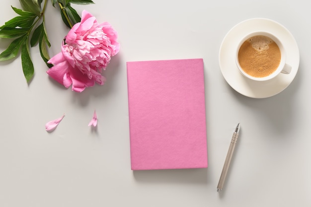 Creatief vrouwelijk model met koffiekopje pioenroos bloemen schetsboek voor planning