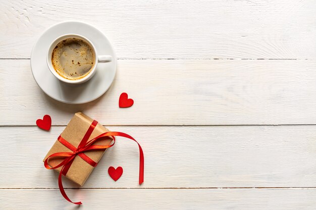 Creatieve bovenaanzicht plat lag romantische compositie. Hete espresso koffiemok met rode geschenkharten en ambachtelijke huidige doos. Valentijnsdag