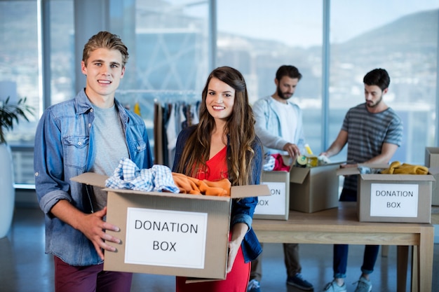 Creatieve business team kleren sorteren in donatie box op kantoor