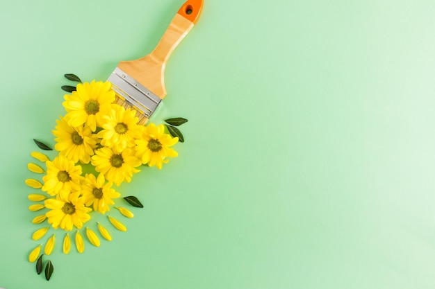 Creatieve compositie met een penseel en gele bloemen schilderen het leven met felle kleuren het concept van transformatie en alles wat nieuw is een kopieerruimte