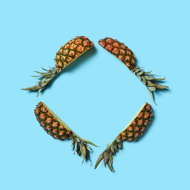 Creatieve compositie van stukjes ananas in de vorm van een frame op een blauwe achtergrond met kopieerruimte