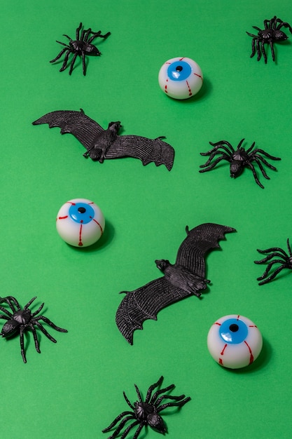 Creatieve Halloween-lay-out met spinnenvleermuizen en oogbollen op groene achtergrond