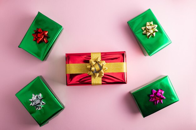 Foto creatieve handgemaakte kerstgroene rode en zilveren glanzende geschenkkistjes met decor op pastelroze achtergrond top viewxa