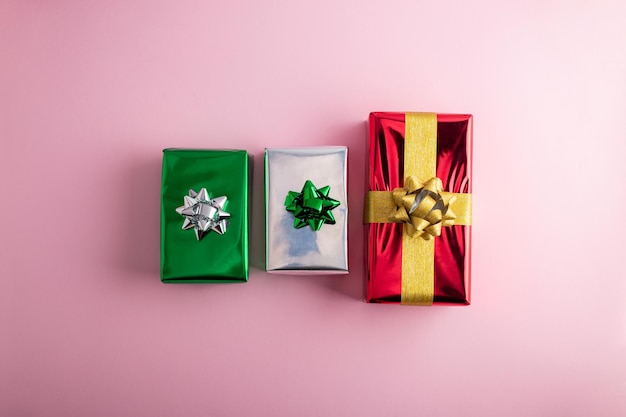 Creatieve handgemaakte kerstgroene rode en zilveren glanzende geschenkkistjes met decor op pastelroze achtergrond top viewxA