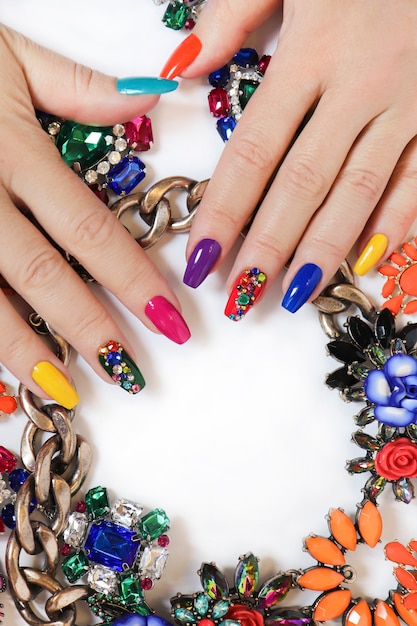 Creatieve heldere verzadigde manicure op lange nagels met strass steentjes.