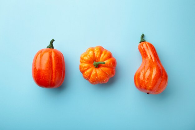 Creatieve herfstsamenstelling. Oranje pompoenen op blauwe achtergrond.