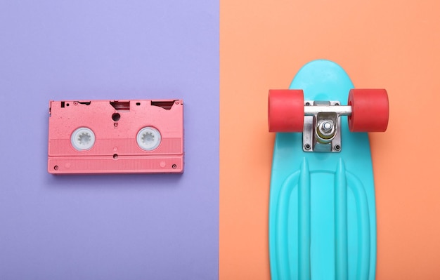 Creatieve hipster lay-out Roze videocassette en penny board op mint blauwe achtergrond Minimalisme Plat lag Bovenaanzicht