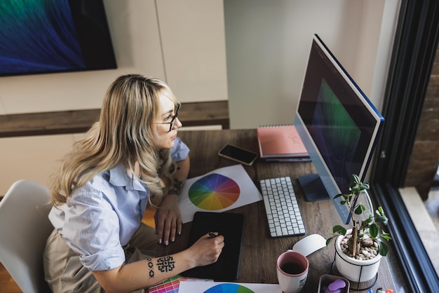 Creatieve jonge vrouw die attent kijkt terwijl ze comfortabel thuis op de computer werkt.