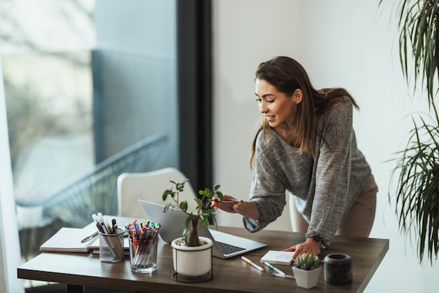 Creatieve jonge vrouw die op laptop werkt op kantoor aan huis.