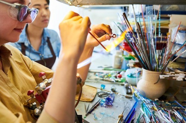 Creatieve jonge vrouw smelten glas in brander