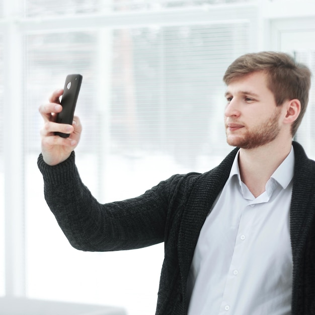 Creatieve jongeman maakt een selfie in een modern kantoor