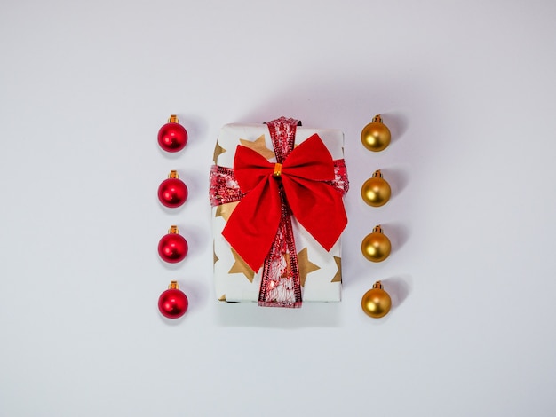 Creatieve Kerstsamenstelling gemaakt van geschenkdoos met rood lint en kerstballen kerstversiering goud en rood plat lag bovenaanzicht