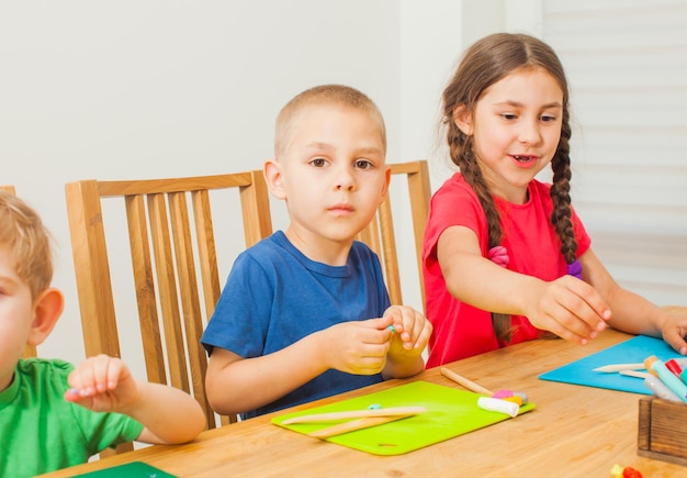 Creatieve kinderen hebben plezier samen met kleurrijke boetseerklei aan tafel. Tijd samen met vrienden