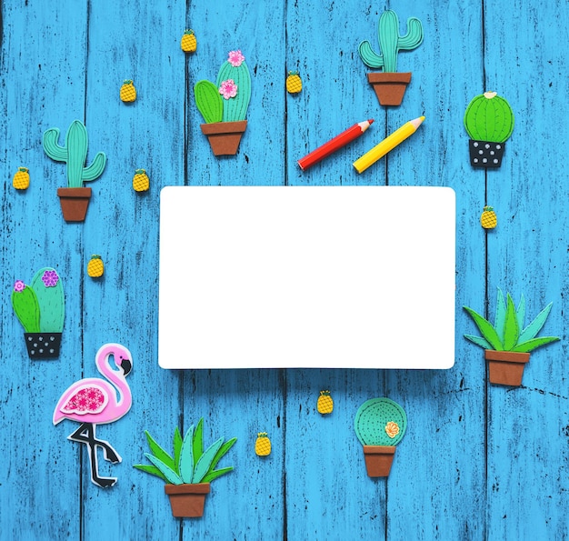 Creatieve kleurrijke achtergrond met trendy hand getrokken en gesneden elementen cactussen ananas roze flamingo en blanco boek voor tekst tropische exotische handgemaakte set op blauwe textuur tafelblad weergave