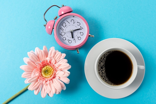 Foto creatieve lay-out gemaakt met kopje koffie en wekker op blauwe achtergrond.