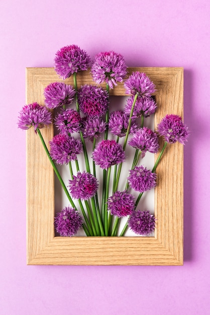 Creatieve lay-out gemaakt met paarse bloemen in fotolijst op paars. Plat liggen. Bloemsamenstelling