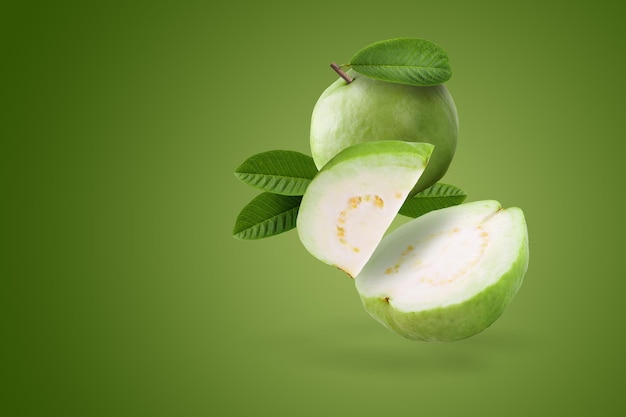 Creatieve lay-out gemaakt van geheel en plakje guavefruit en bladeren op een groene achtergrond