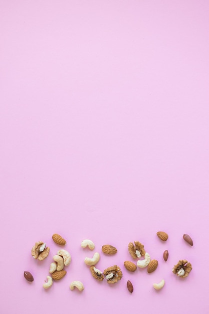 Creatieve lay-out gemaakt van hazelnootnoten amandelen walnoot pinda cashewnoten op roze achtergrond plat leggen