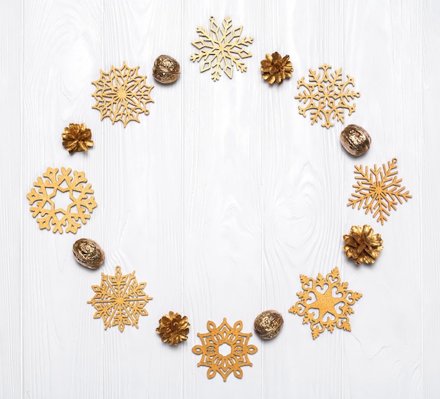 Creatieve lay-out van nieuwjaarsdecoraties Gouden sneeuwvlokken dennenappels en noten
