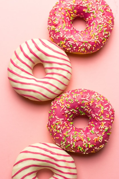 Creatieve layout gemaakt van roze geglazuurde donuts. Plat liggen. Voedsel concept. Macro concept. Diverse versierd donuts op zacht roze achtergrond. Zoete en kleurrijke donuts