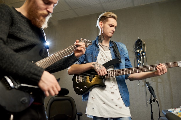 Creatieve mannen die gitaren in studio spelen