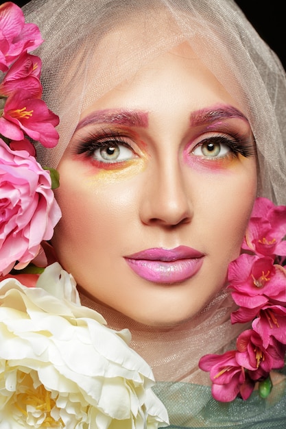 Creatieve mode schoonheid portret van mooie jonge vrouw met bloem make-up