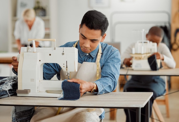 Creatieve modeontwerper die naaivaardigheden leert op denimkleding in een kledingfabriek Jonge en modieuze student die een naaimachine gebruikt in een werkplaats die met stijlvolle stof werkt