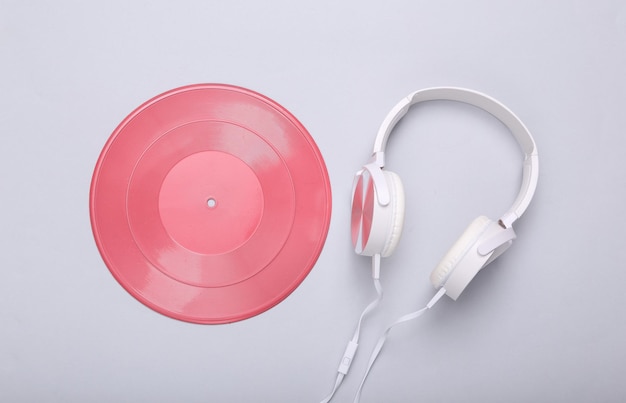 Creatieve muzieklay-out Roze vinylplaat en koptelefoon op grijze achtergrond Minimalisme Plat lag Bovenaanzicht