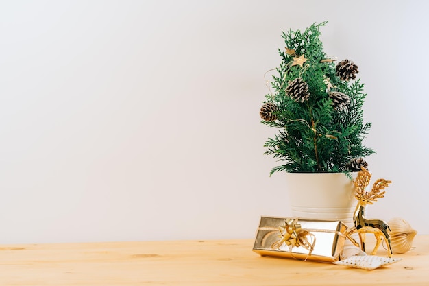 Creatieve natuurlijke miniatuur kerstboom in pot op houten tafel met geschenkdozen en wit