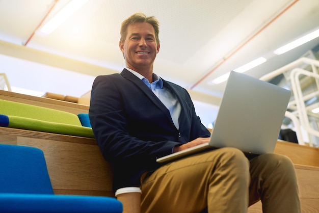 Creatieve omgeving houdt mijn ideeën fris Portret van een succesvolle zakenman die zijn laptop gebruikt terwijl hij in een modern kantoor zit