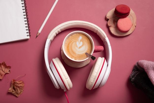 Creatieve platte compositie met koffiekop en koptelefoon op donkerroze kleurachtergrond Creatieve muziek ontspan online concept