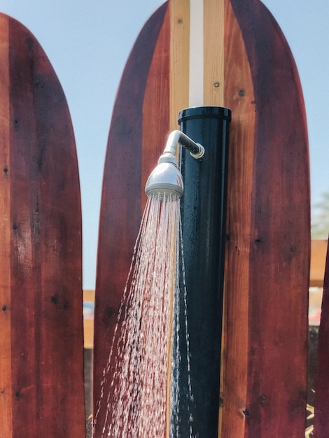 Creatieve stranddouche met douchekop op surfplank bij warm zonnig weer