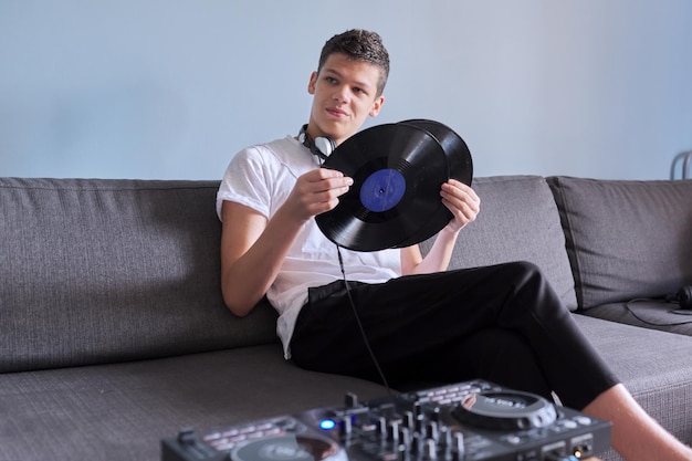 Creatieve tienerjongen met vinylplaten, jonge man in koptelefoon geïnteresseerd in muziek, hobby's en vrije tijd, grijze achtergrond