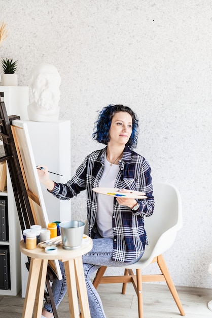 Creatieve vrouwelijke kunstenaar die een foto schildert die in haar atelier werkt