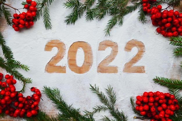 Creatieve wenskaart Happy New Year 2022 Meelcijfers op een houten ondergrond en groene takken