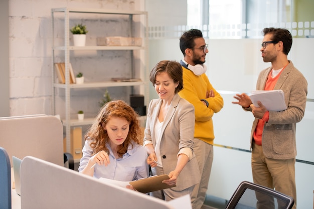 Creatieve werknemers die met gegevens in kantoor werken: productmanager die verkoopplan aanbiedt aan collega terwijl mannen papierwerk bespreken