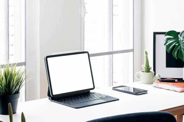 Creatieve werkruimte met leeg scherm tablet en gadget op houten tafel in moderne witte kamer.